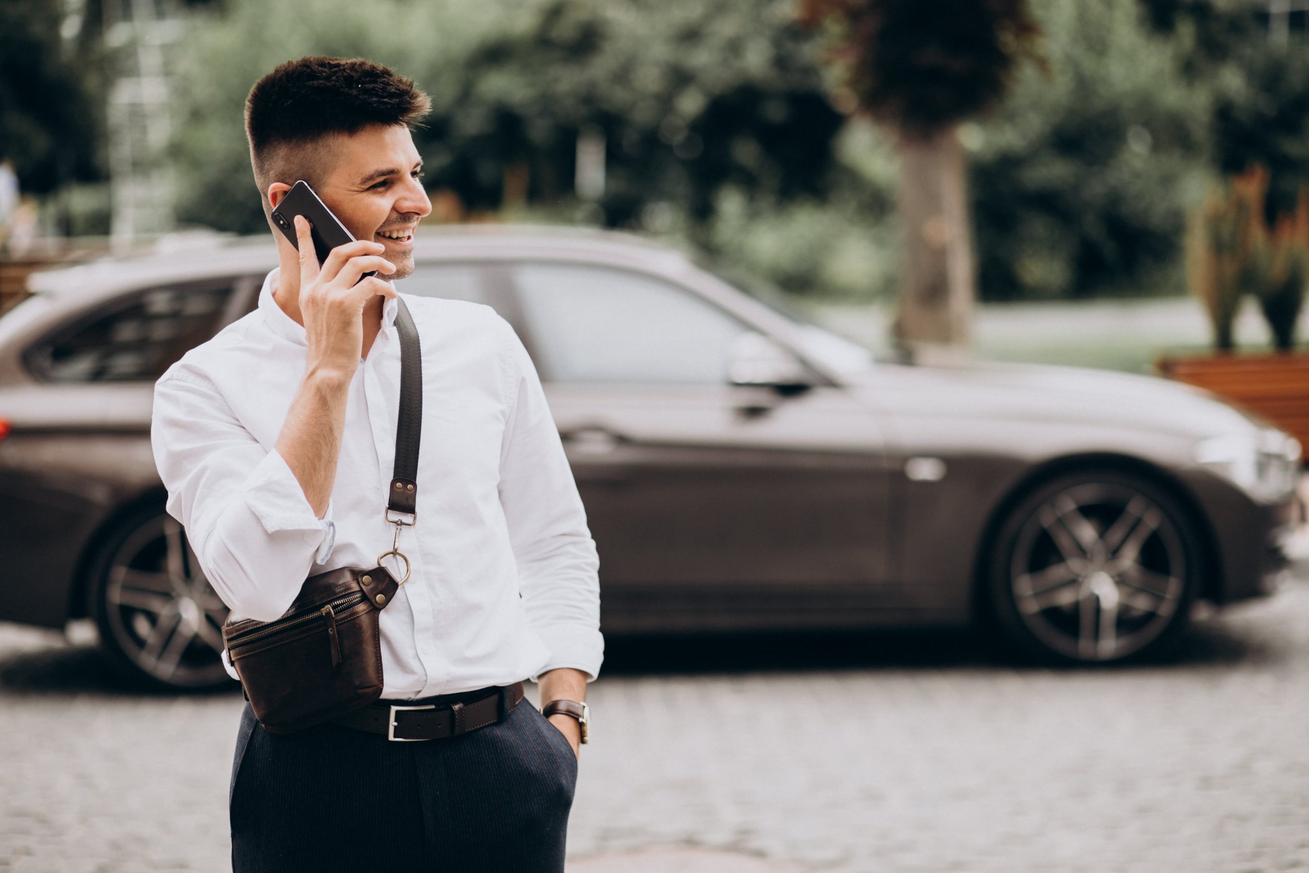 boldog férfi autóval és telefonnal
